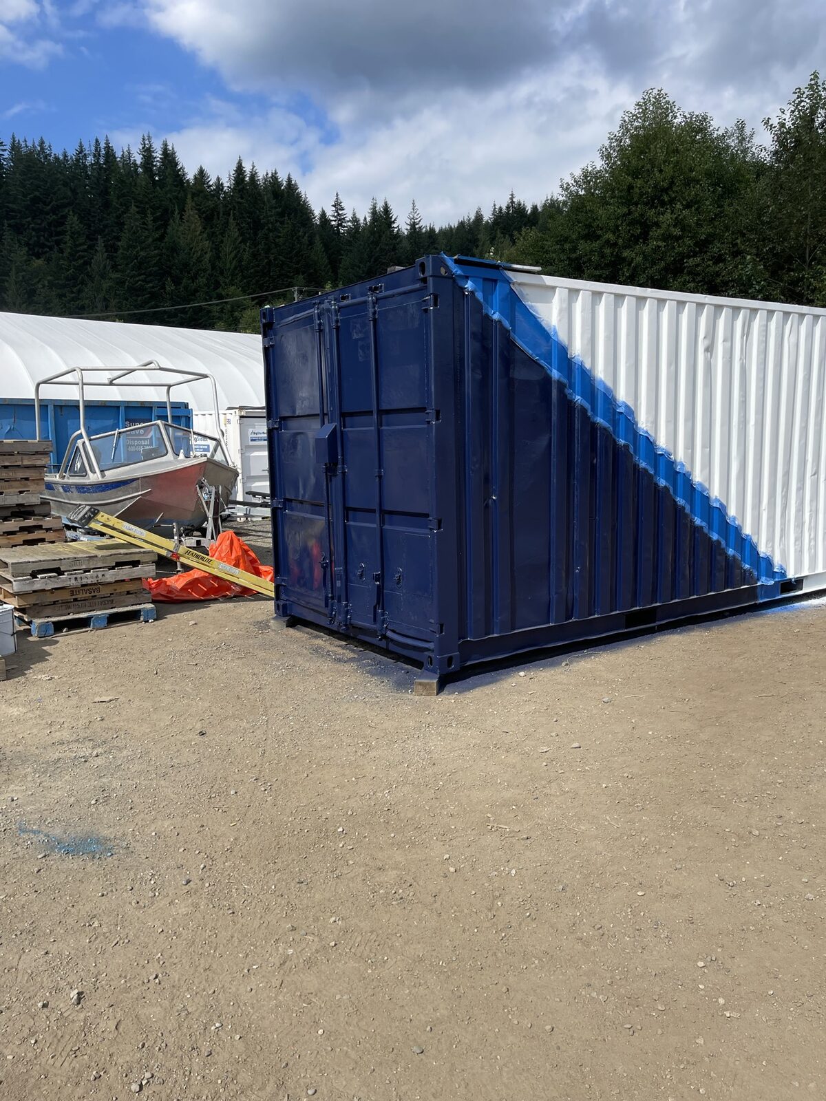 The container's door end painted deep navy, with the white side and bright blue diagonal stripe visible behind it.