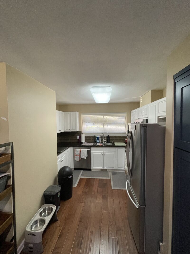 A galley kitchen and hallway in the same house, walls still yellow before painting.