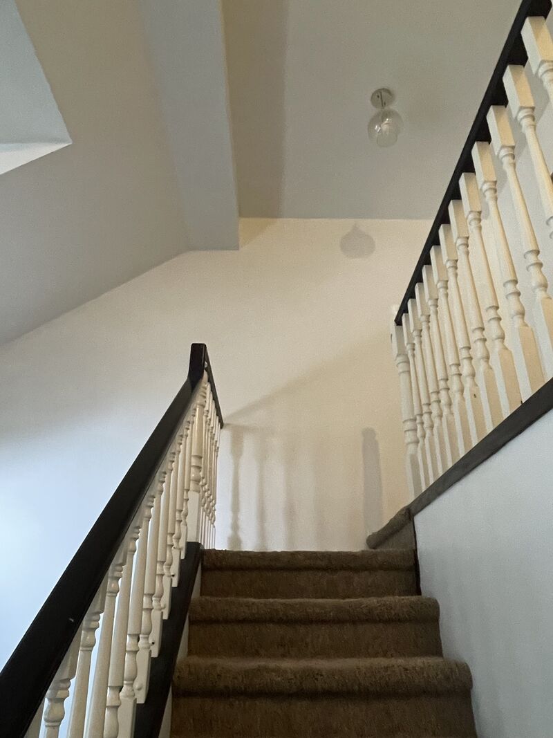The staircase after painting, looking down past the white spindles and dark handrail.