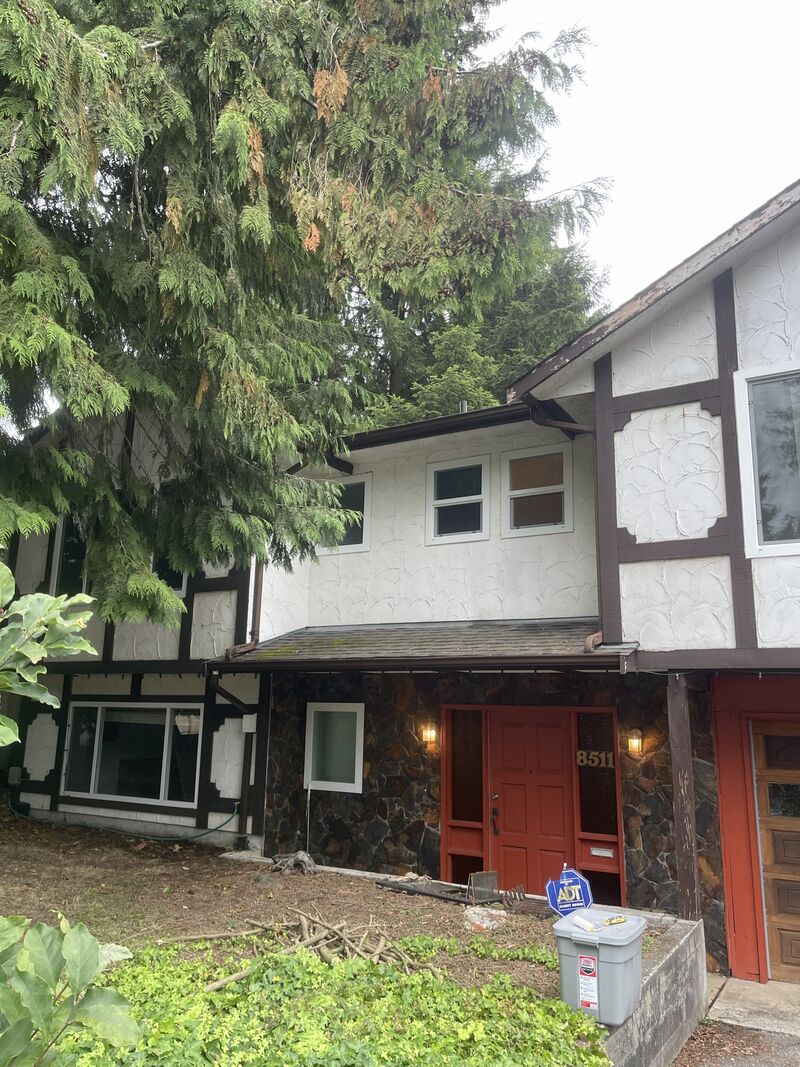 Front of the Tudor-style house with its red door and stone base.