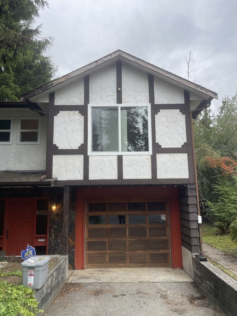 The garage end of the house with white stucco panels and dark trim.
