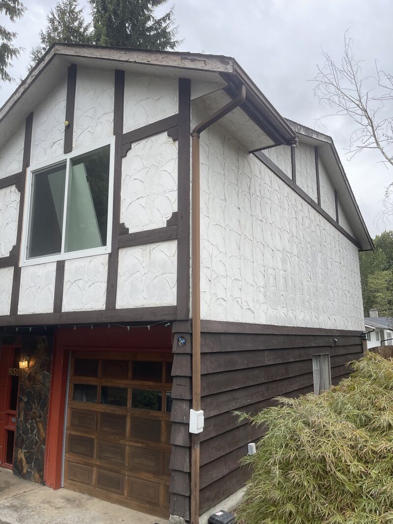 Side of the house with the stucco and dark trim running back from the garage.