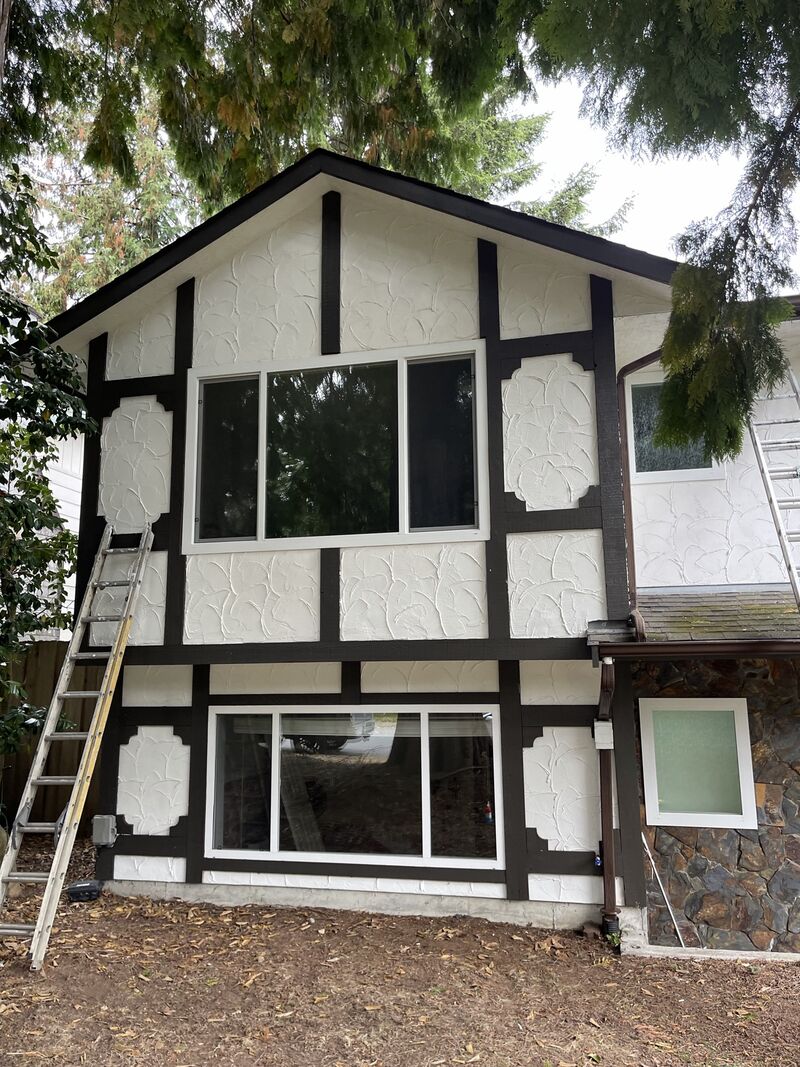 After: the same gable end painted, with a ladder still against the wall.