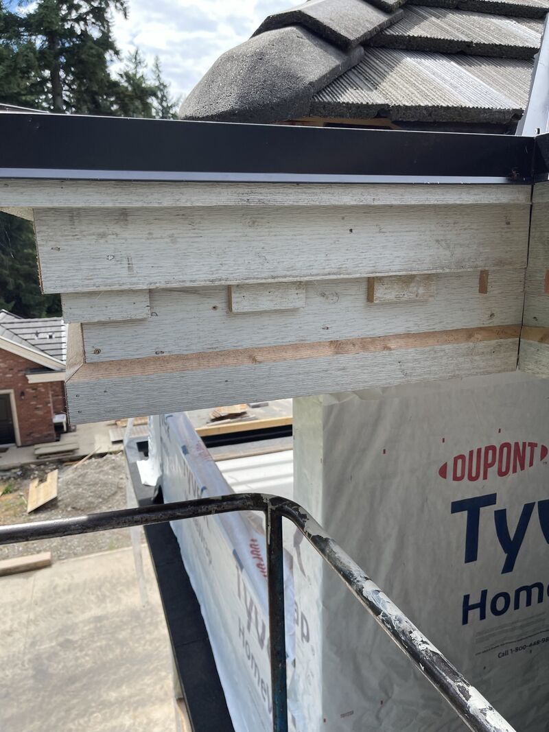 Wood trim and fascia below the roof edge during the work, house wrap behind.