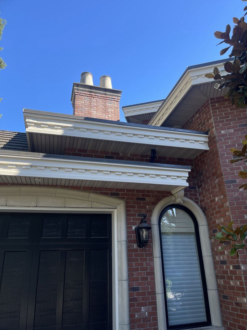 Cream-painted trim, fascia and moulding on a brick house with an arched window.