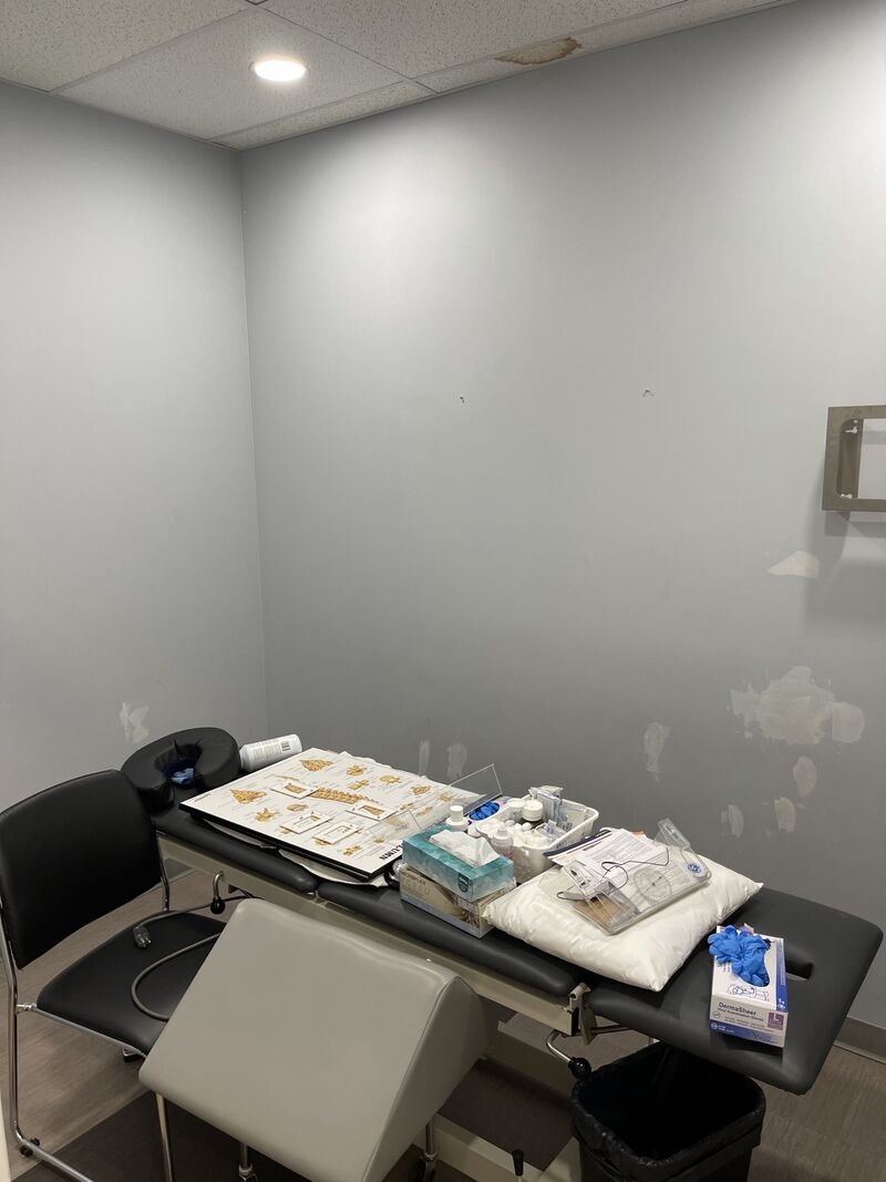 A clinic treatment room with patched spots on the grey walls before painting.