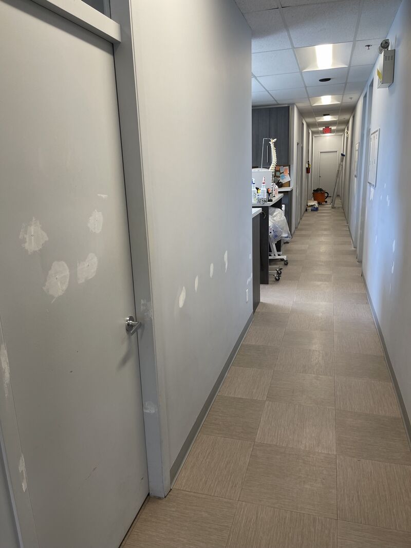 A long clinic hallway with patch marks along the walls before painting.