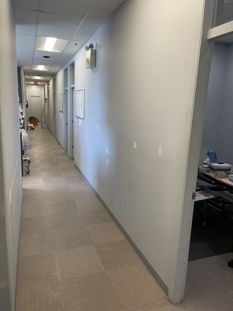 The clinic hallway from the other end, doors along one side.
